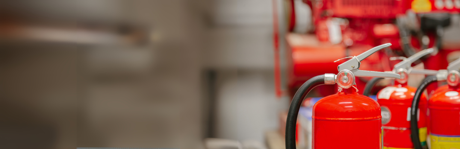 Row of bright red fire extinguishers with focus on one in the foreground.