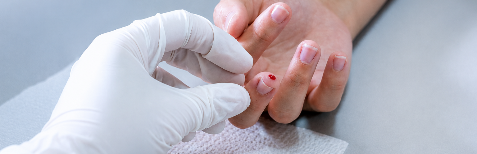 Medical person examining finger with small blood prick.